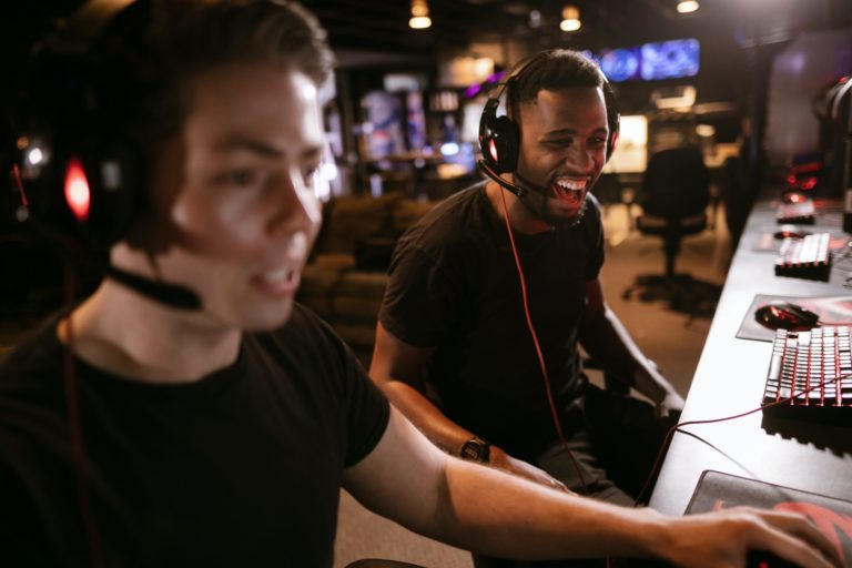 Zwei junge Personen, die am Schreibtisch Computerspiele spielen