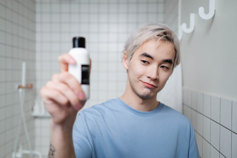Junger Mann in Bad mit Duschgel in der Hand